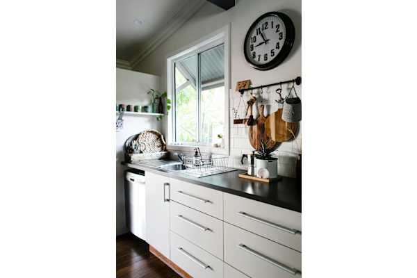 A kitchen with white cabinets and a black countertop with a clock on the wall.